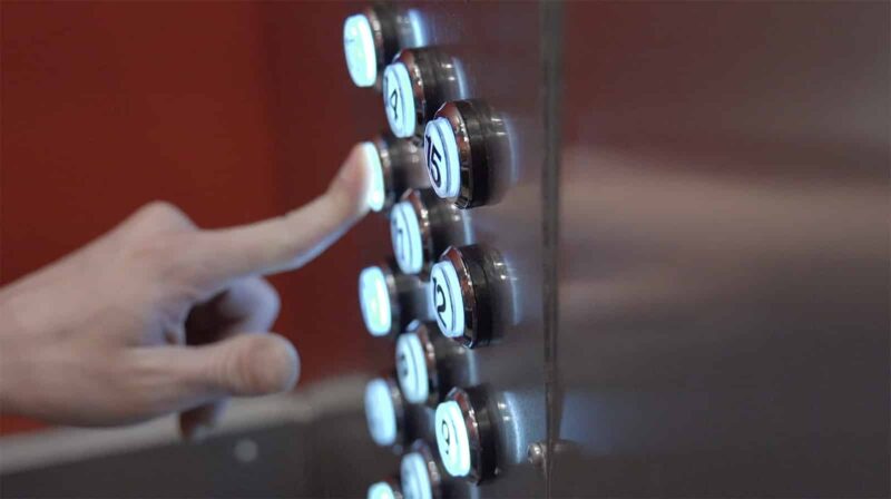 Finger pushing an elevator button close up in the Escape Room, Trudeau Towers, at Lockdown Ottawa Escape Rooms